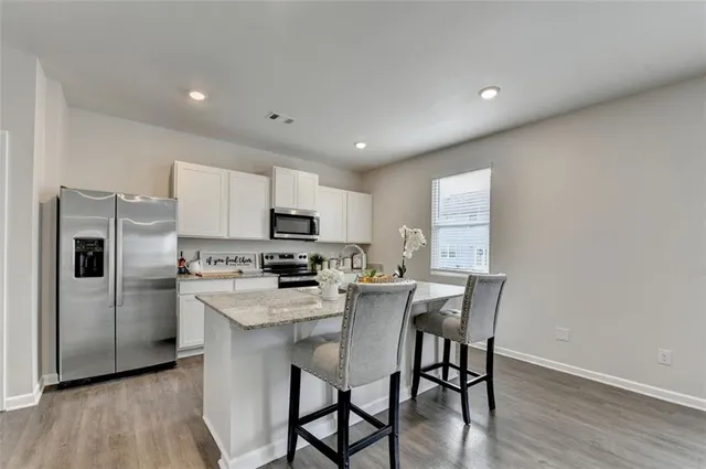 a kitchen with stainless steel appliances a dining table chairs microwave and refrigerator