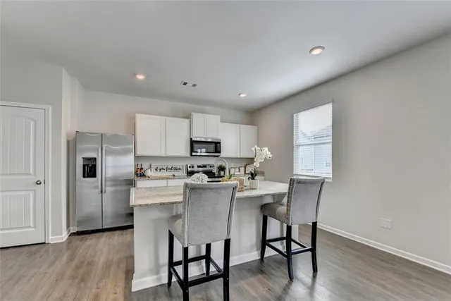 a kitchen with stainless steel appliances granite countertop a table chairs refrigerator and sink