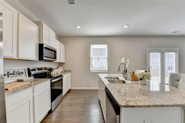 a kitchen with granite countertop white cabinets stainless steel appliances and wooden floor