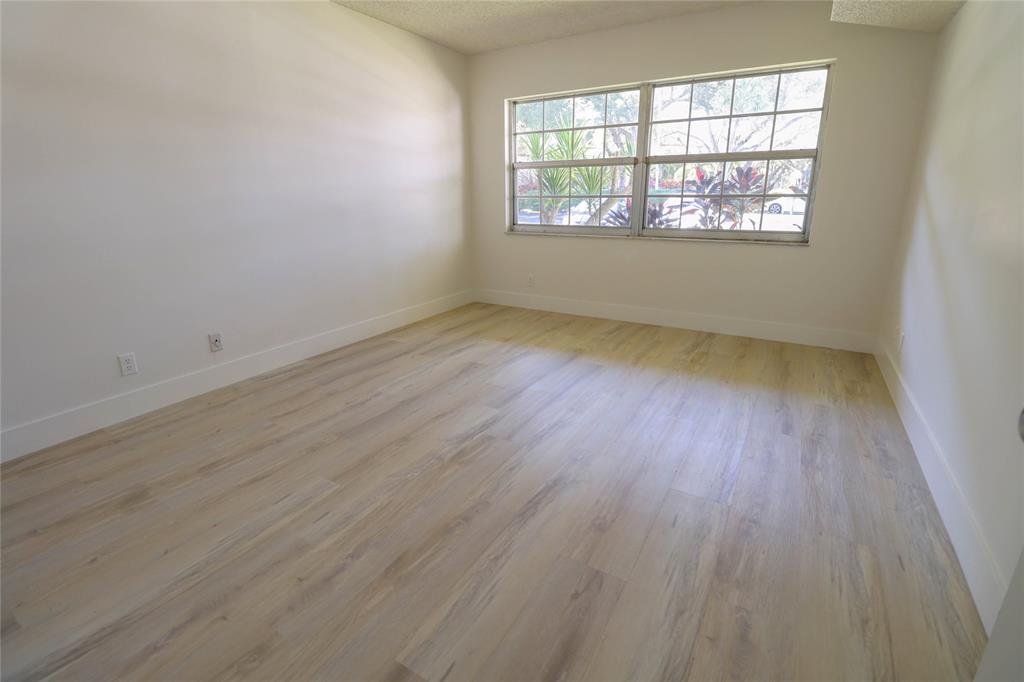 4007 North Cypress Drive, Unit 103 Pompano Beach, FL 33069 - Photo 14 of 25 an empty room with wooden floor and windows