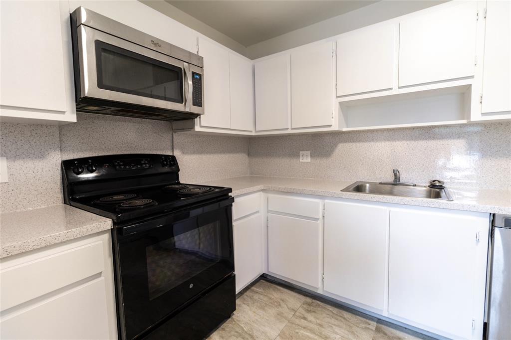 4007 North Cypress Drive, Unit 103 Pompano Beach, FL 33069 - Photo 24 of 25 a kitchen with stainless steel appliances granite countertop white cabinets and a stove top oven