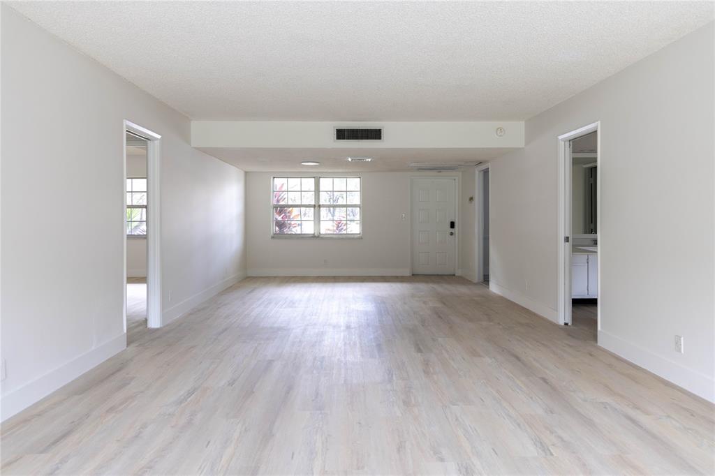 4007 North Cypress Drive, Unit 103 Pompano Beach, FL 33069 - Photo 3 of 25 an empty room with wooden floor and windows