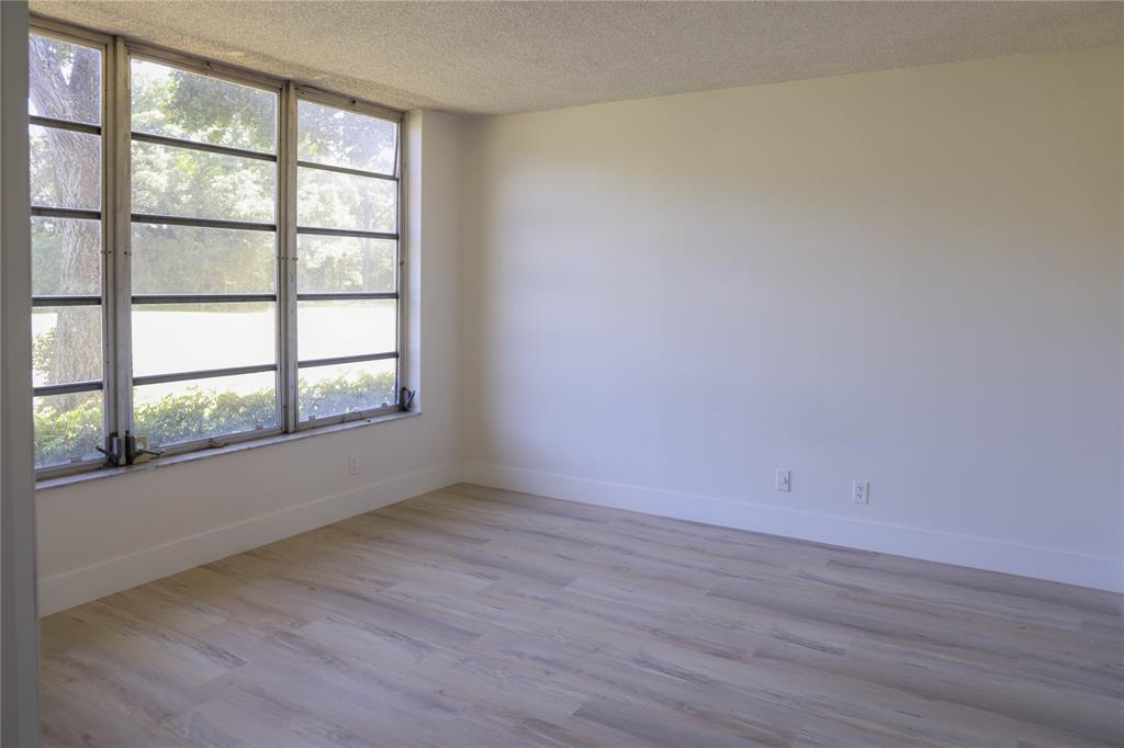 4007 North Cypress Drive, Unit 103 Pompano Beach, FL 33069 - Photo 6 of 25 an empty room with wooden floor and windows