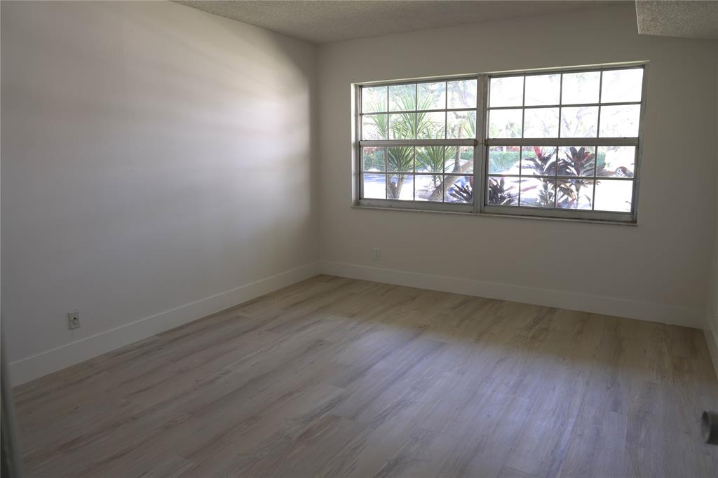 4007 North Cypress Drive, Unit 103 Pompano Beach, FL 33069 - Photo 7 of 25 an empty room with wooden floor and windows