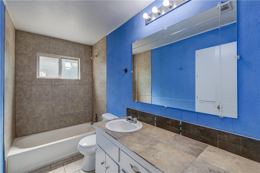 1006 Fiesta Street, Unit A Austin, TX 78702 - Photo 8 of 12 a bathroom with a granite countertop toilet a sink and bathtub
