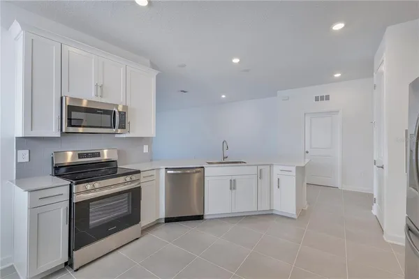 a kitchen with granite countertop white cabinets and stainless steel appliances