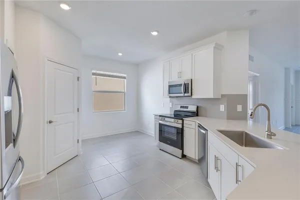 a kitchen with white cabinets a sink stove and refrigerator