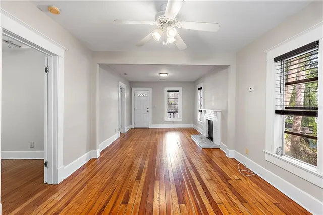a view of empty room with wooden floor and fan