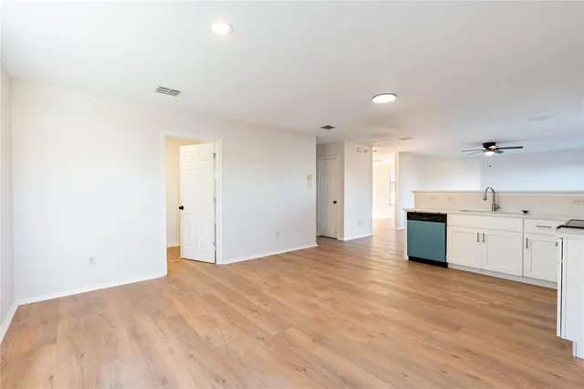 a view of a kitchen with a sink and dishwasher a stove top oven with wooden floor