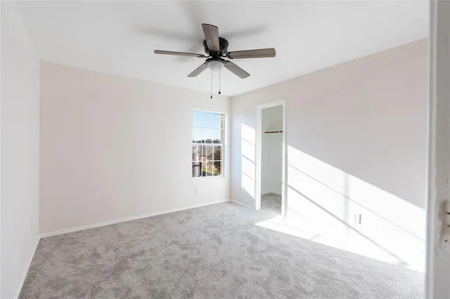 an empty room with a window and a ceiling fan
