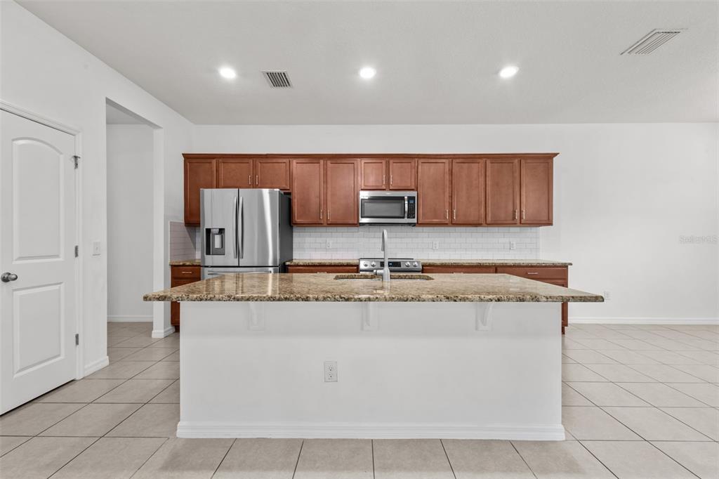 12124 Lake Boulevard Trinity, FL 34655 - Photo 11 of 31 a kitchen with stainless steel appliances granite countertop a sink a stove a microwave and a refrigerator