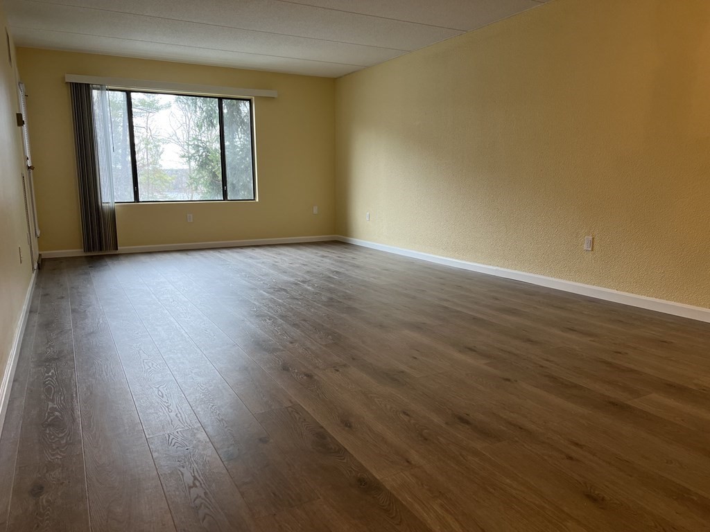 1550 Worcester Road, Unit 114 Framingham, MA 01702 - Photo 4 of 29 a view of an empty room with wooden floor and a window