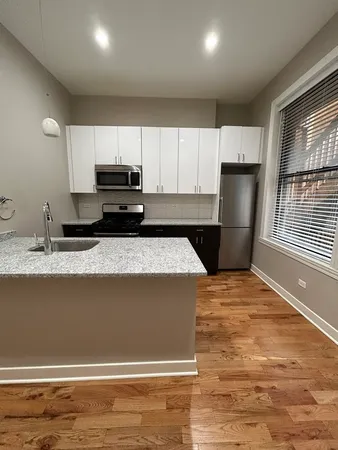 a kitchen with a sink a stove top oven and wooden floor