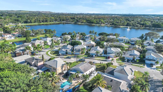 an aerial view of lake and residential houses with outdoor space and swimming pool
