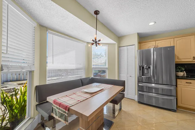 a kitchen with a refrigerator a stove a sink dishwasher a dining table and chairs with wooden floor