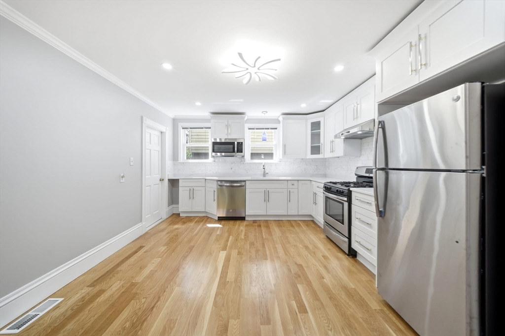 29 Hanson Street, Unit 1 Somerville, MA 02143 - Photo 16 of 40 a kitchen with stainless steel appliances granite countertop a refrigerator sink and white cabinets