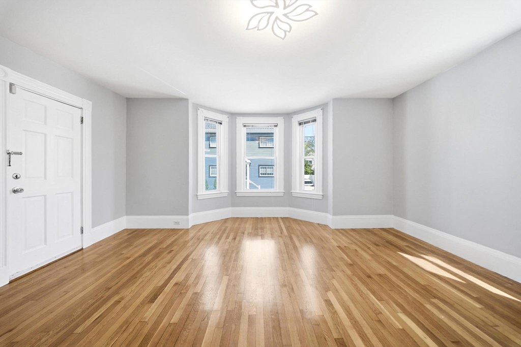 29 Hanson Street, Unit 1 Somerville, MA 02143 - Photo 10 of 40 a view of an empty room with wooden floor and window