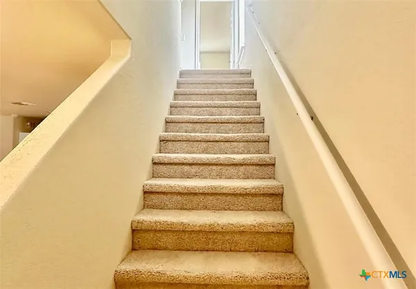 a view of an empty room with wooden floor and a bathroom