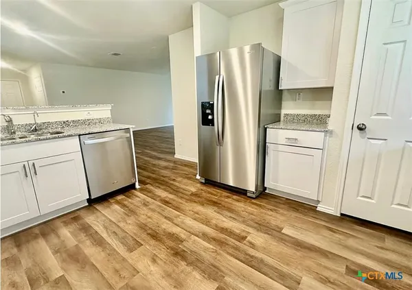a kitchen with granite countertop a stove top oven sink and cabinets