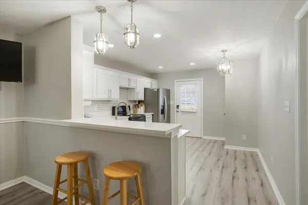 a kitchen with stainless steel appliances granite countertop a dining table chairs refrigerator and microwave