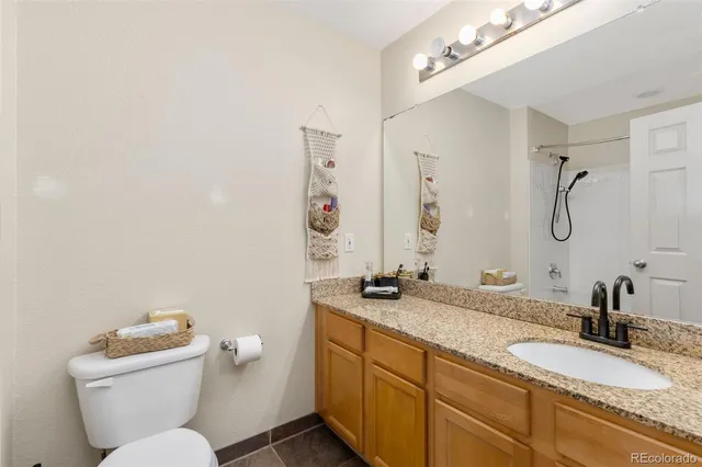 a bathroom with a granite countertop sink mirror vanity and toilet