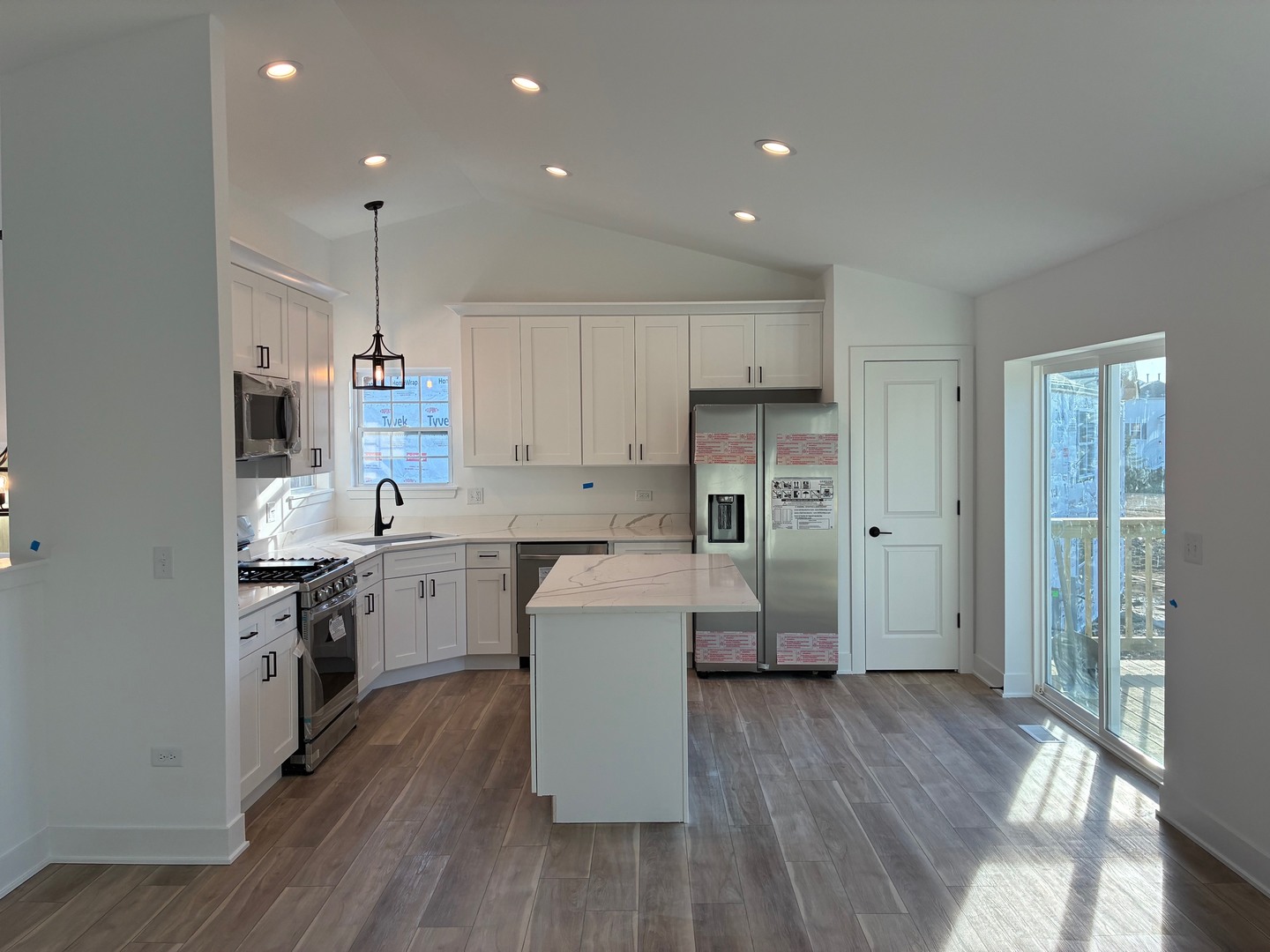 931 Saddle Ridge Drive Joliet, IL 60432 - Photo 5 of 23 a kitchen with kitchen island wooden floors white cabinets and stainless steel appliances