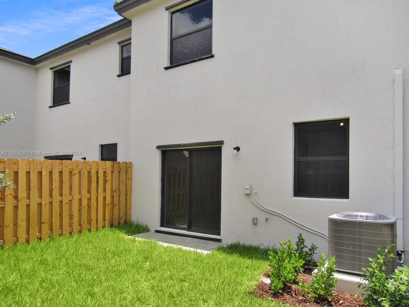 13401 Southwest 287th Street, Unit 13401 Homestead, FL 33033 - Photo 28 of 29 a backyard of a house with potted plants and wooden wall