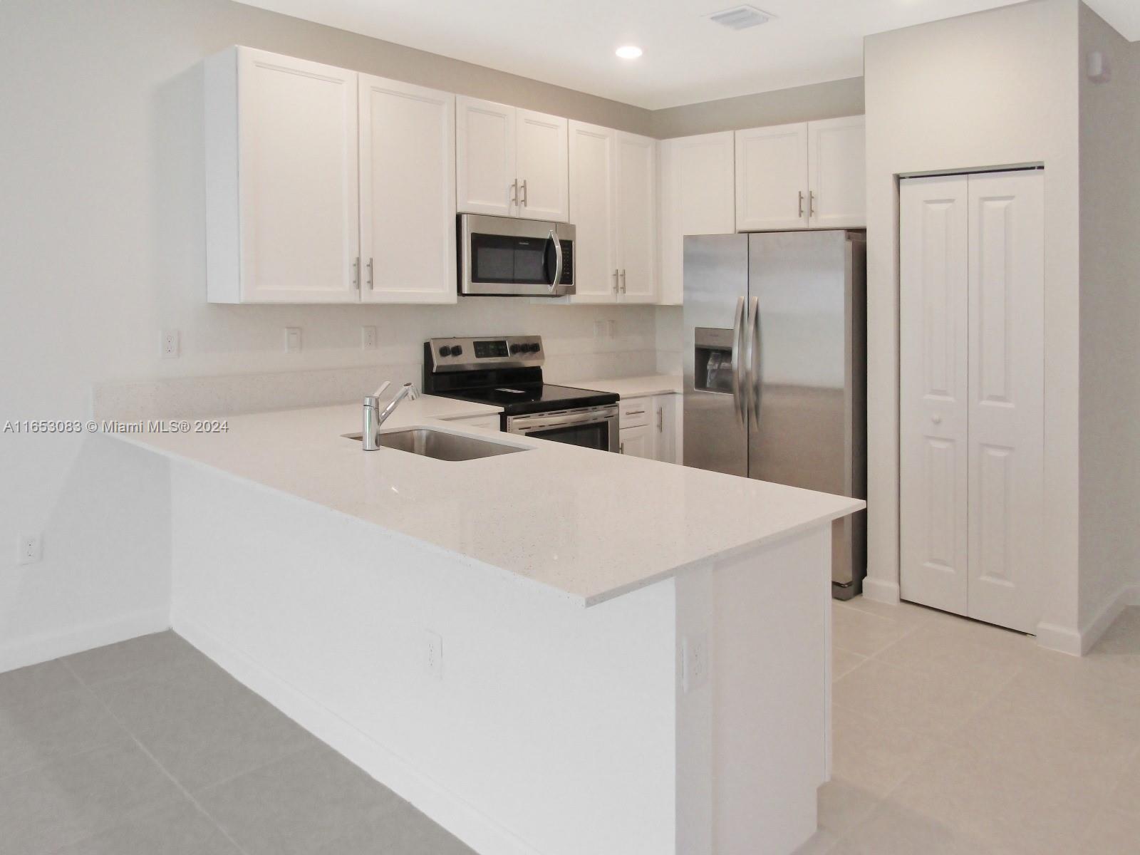 13401 Southwest 287th Street, Unit 13401 Homestead, FL 33033 - Photo 6 of 29 a kitchen with a refrigerator a microwave a sink and cabinets