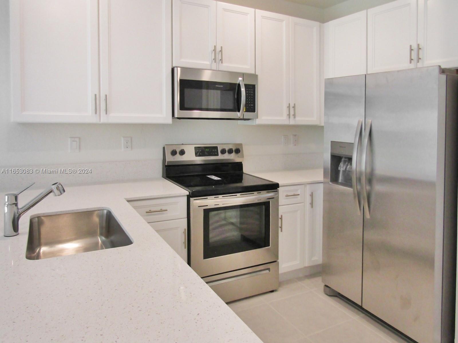 13401 Southwest 287th Street, Unit 13401 Homestead, FL 33033 - Photo 7 of 29 a kitchen with white cabinets and stainless steel appliances