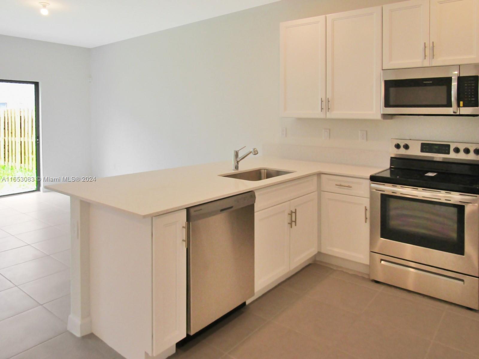 13401 Southwest 287th Street, Unit 13401 Homestead, FL 33033 - Photo 8 of 29 a kitchen with white cabinets stainless steel appliances and sink