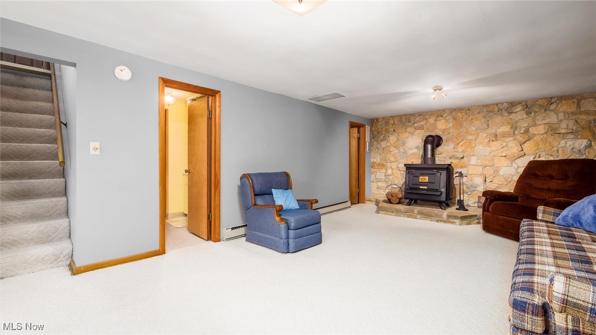 165 Old Rix Mills Road New Concord, OH 43762 - Photo 16 of 34 Living area with a wood stove, carpet, stairway, baseboard heating, and baseboards