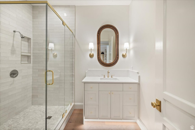 478 South Maple Lakes Drive Mapleton, UT 84664 - Photo 36 of 51 Bathroom featuring a glass-enclosed shower with subway tile surround and hexagonal floor tiles, a single vanity with a white countertop and undermount sink, a framed oval mirror, and brass-finish fixtures and hardware