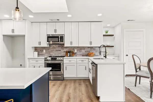 a kitchen with kitchen island a stove a sink and a microwave