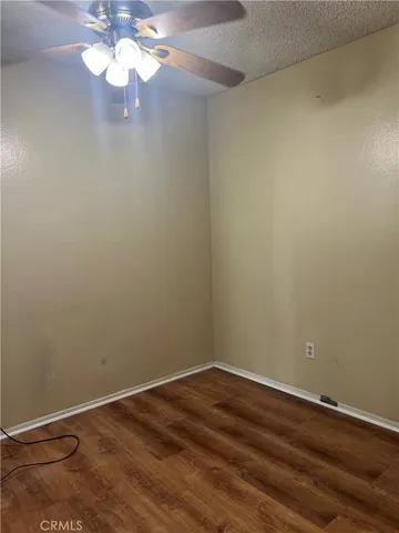 a view of a room with wooden floor and a ceiling fan