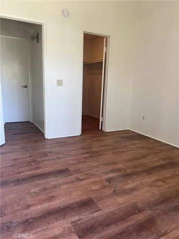 a view of an empty room with wooden floor and closet