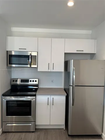 a kitchen with a refrigerator stove and white cabinets