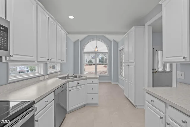 a view of a kitchen with a sink and dishwasher with white cabinets