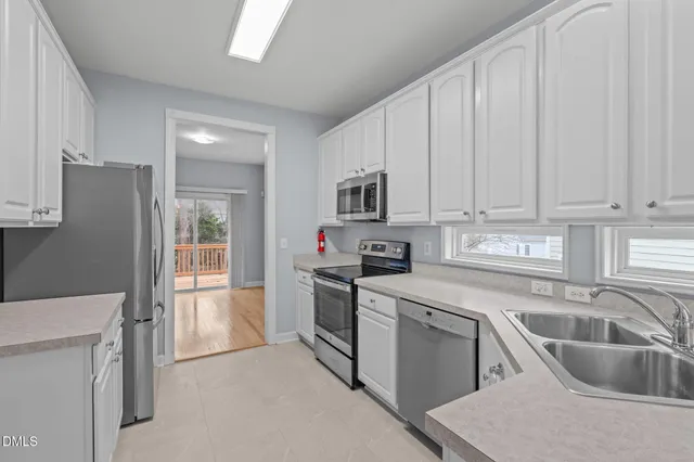 a kitchen with a sink white cabinets and stainless steel appliances