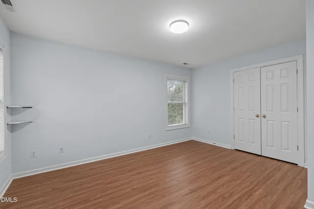 a view of empty room with wooden floor and fan