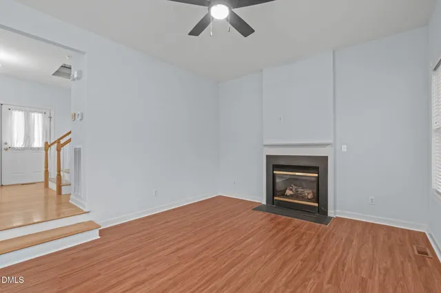 an empty room with wooden floor a fireplace and a window