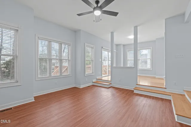 a view of an empty room with wooden floor and a window