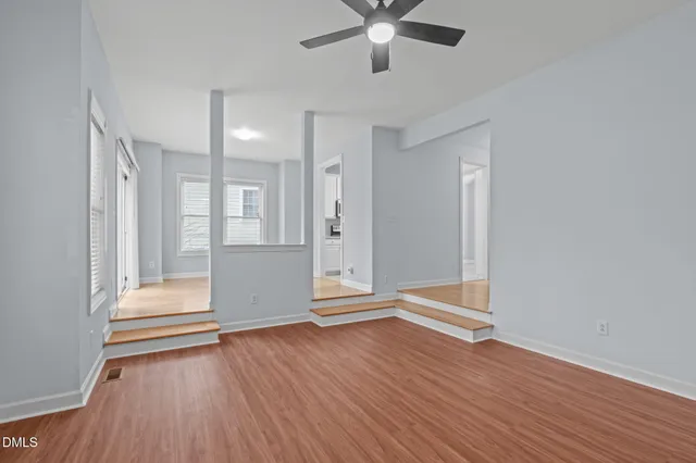 an empty room with wooden floor and windows