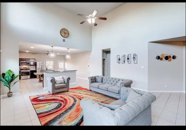 a living room with furniture kitchen view and a chandelier