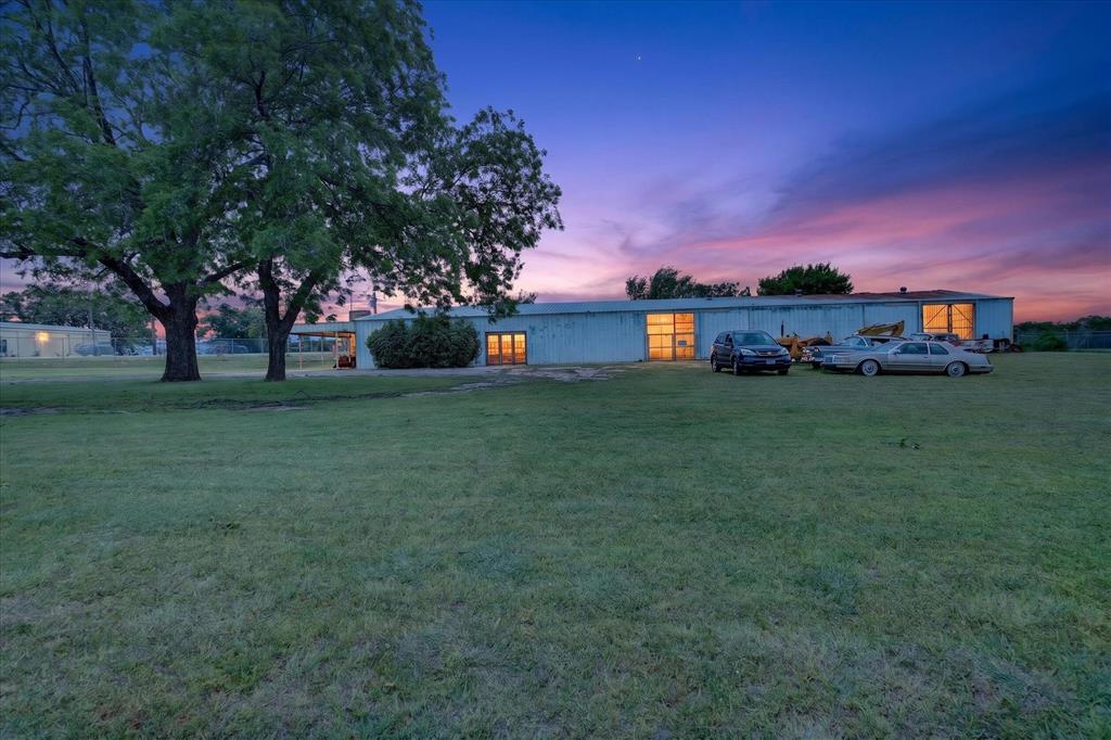 1092 West Highway 199 Springtown, TX 76082 - Photo 1 of 29 one acre lot featuring large mature trees and a metal building with multiple garage door openings