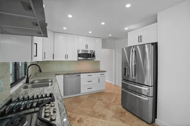 a kitchen with stainless steel appliances granite countertop a refrigerator and a stove