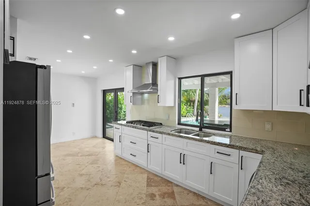 a kitchen with granite countertop a stove a sink and a refrigerator