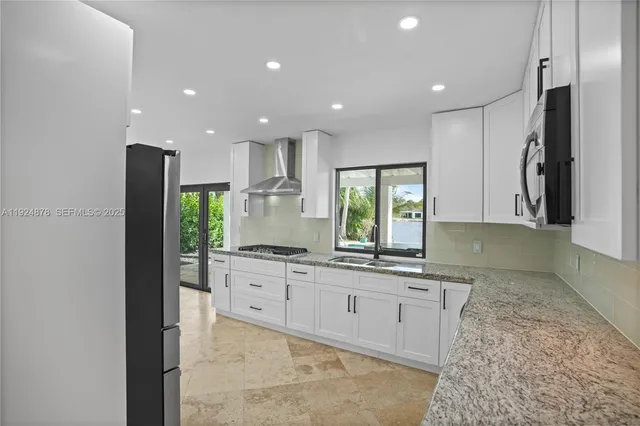 a large kitchen with stainless steel appliances kitchen island granite countertop a refrigerator and a sink