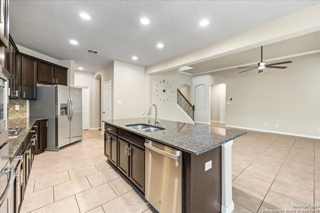 a kitchen with stainless steel appliances granite countertop a sink a stove and a refrigerator