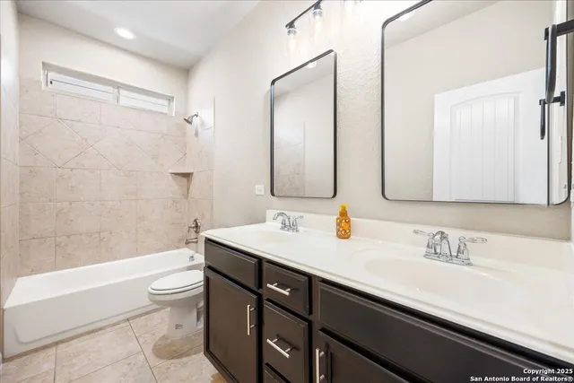 a bathroom with a sink double vanity granite tub shower and a mirror