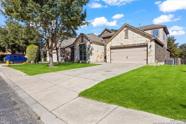 a view of a white house next to a yard with big trees